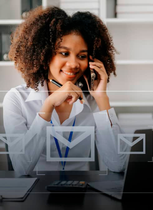 woman with phone in a office looking a laptop